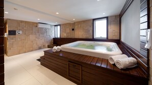 Une salle de bain moderne avec un meuble-lavabo en bois, une grande baignoire et une fenêtre laissant entrer la lumière naturelle.