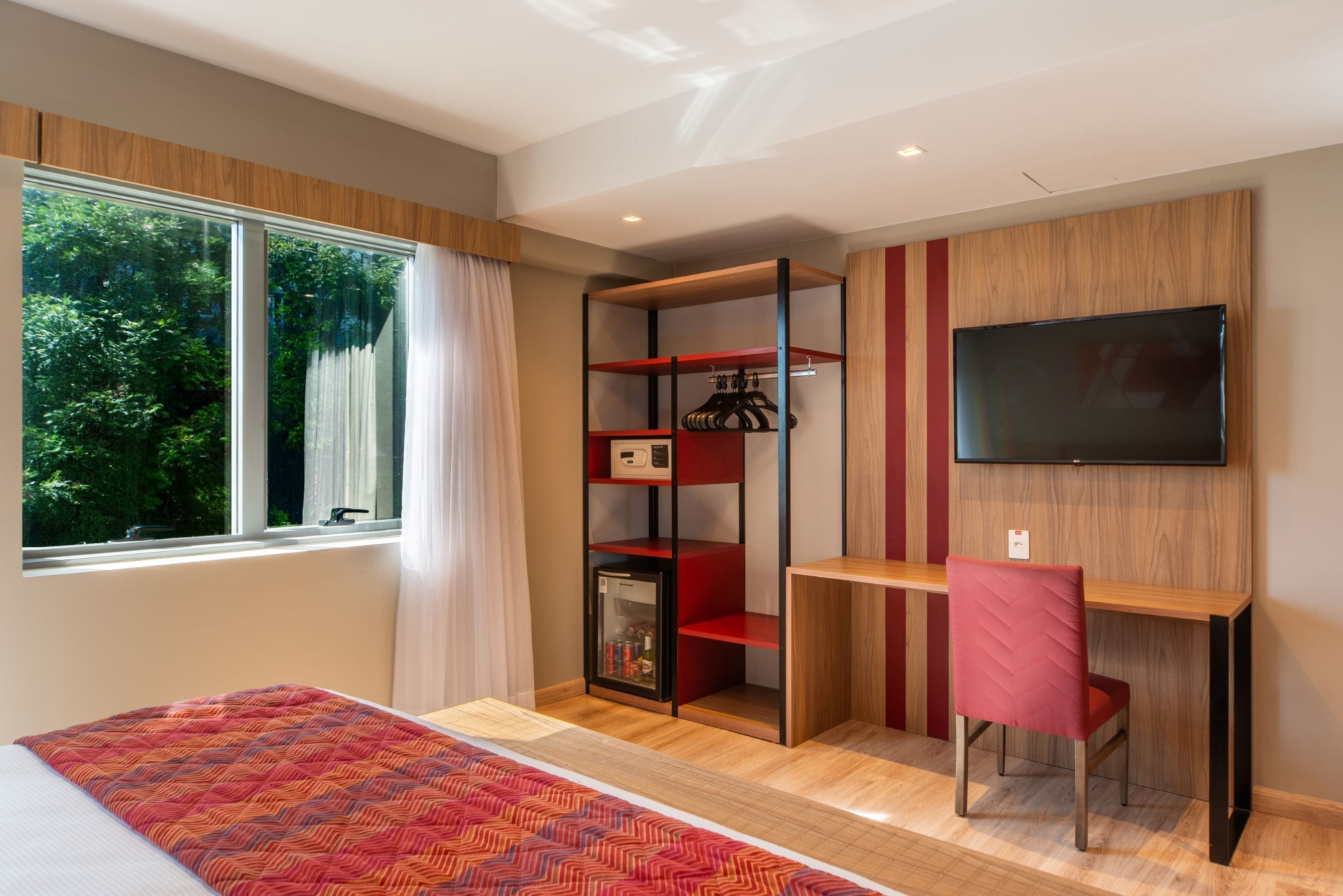 Un dormitorio moderno con una cama, un escritorio, una silla, un televisor y un armario.