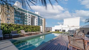 Une piscine sur le toit, dotée de chaises longues et offrant une vue sur les bâtiments modernes.