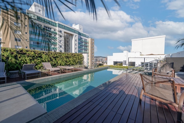A rooftop pool with lounge chairs and a view of modern buildings. - Hotel Laghetto Stilo Higienópolis (Porto Alegre)
