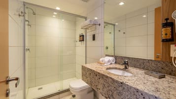 Un baño moderno con cabina de ducha de vidrio, encimera de granito y un espejo grande.
