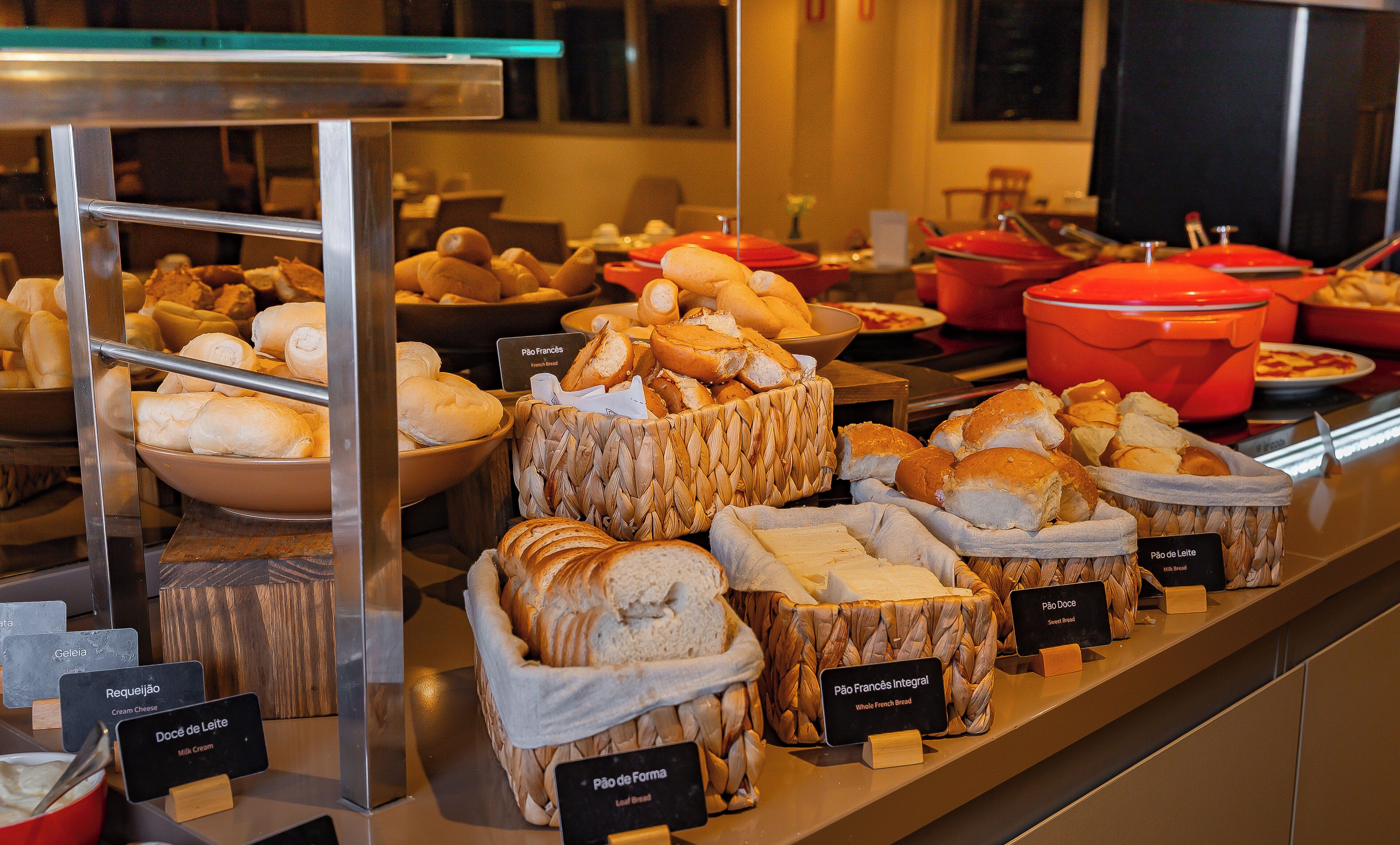 Mostrador de panadería con distintos tipos de pan y pasteles, incluyendo etiquetas para cada uno.