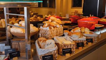Mostrador de panadería con distintos tipos de pan y pasteles, incluyendo etiquetas para cada uno.
