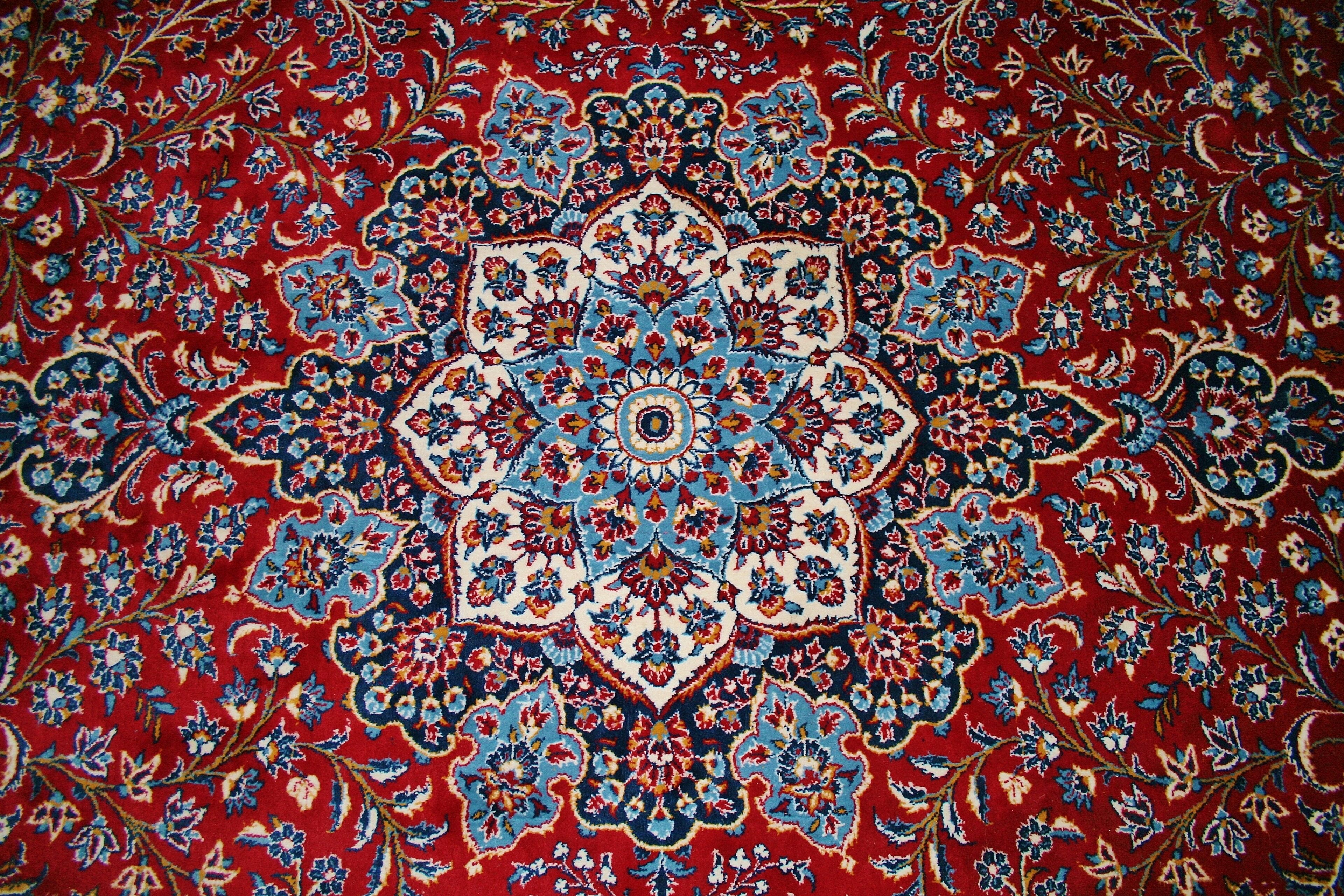 A detailed, symmetrical carpet with a central medallion and floral patterns.