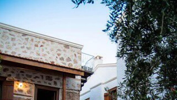 A narrow stone pathway leading to a building with a balcony and wooden shutters. - Courtyard Hotel Kalkan (Kas)