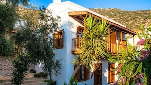 Un edificio blanco con balcones de madera y una pared de piedra.