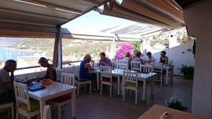 Un espace de restauration en plein air, avec des tables et des chaises blanches, offrant une vue imprenable sur un paysage côtier pittoresque.