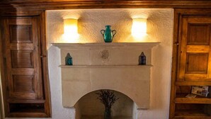 Una chimenea con dos apliques de pared, un jarrón decorativo y un estante pequeño con libros.