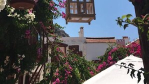 A courtyard with a hanging birdcage, potted plants, and a white umbrella. - Courtyard Hotel Kalkan (Kas)