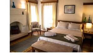 Une chambre d’hôtel avec un lit, une chaise, une cheminée et un tableau au mur.
