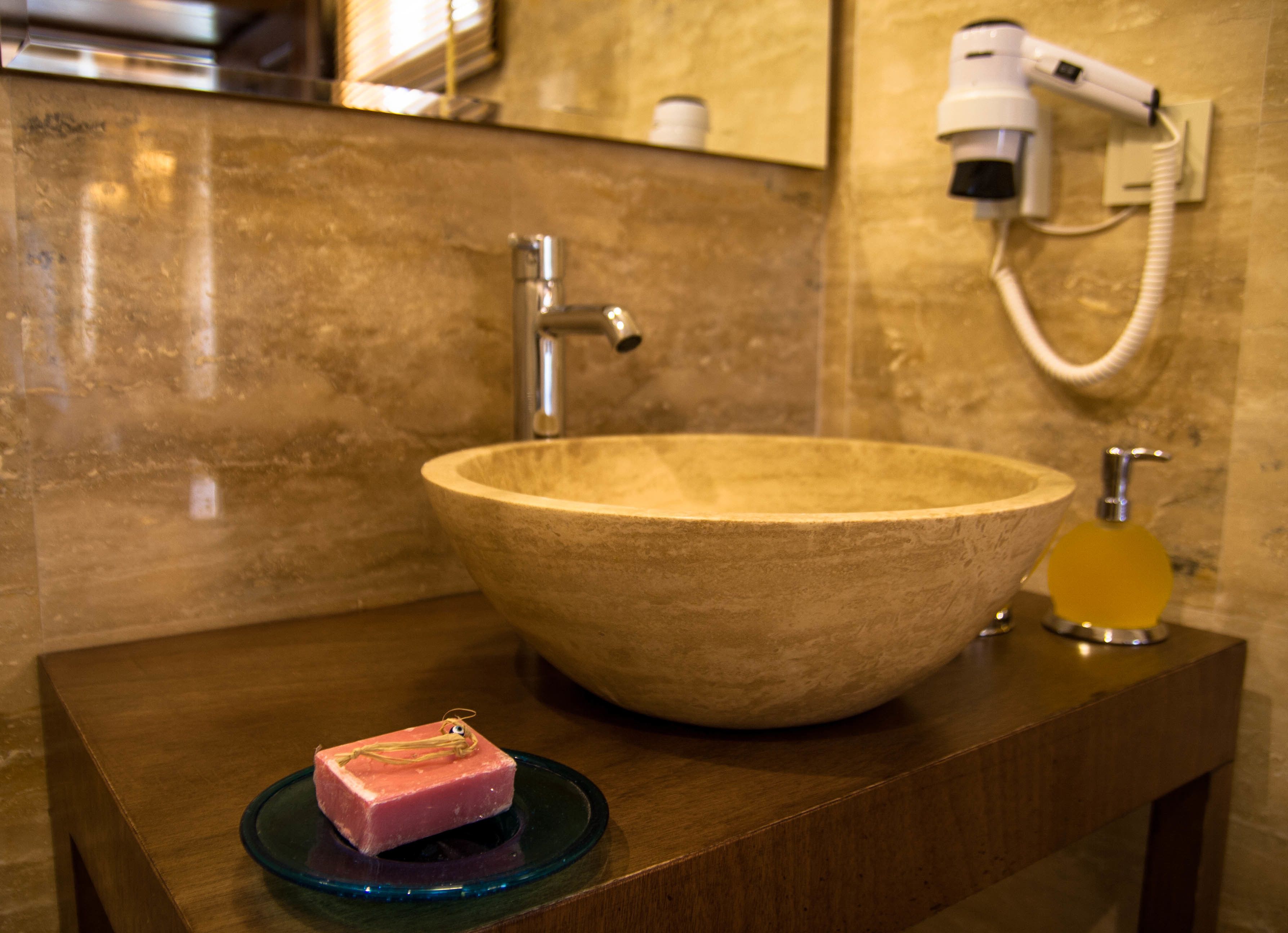 A bathroom with a large wooden sink, a handheld hair dryer, and a soap dish with a bar of soap.