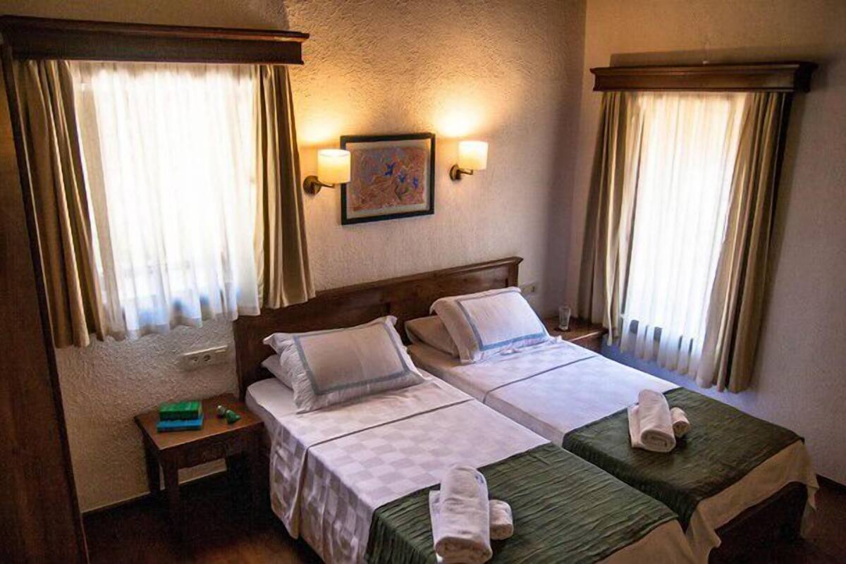 A hotel room with two beds, a nightstand, and a painting on the wall.