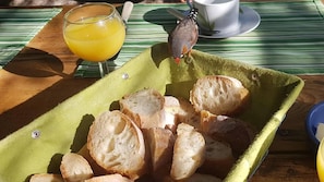 A table with a green tray holding several slices of bread, a glass of orange juice, and a cup with a saucer.