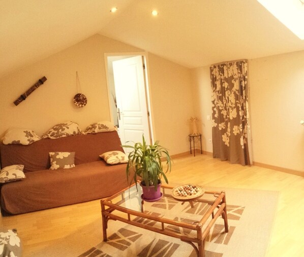 A living room with a brown sofa, a glass coffee table, and a potted plant.