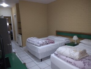 A hotel room with two single beds, a green side table, a white lamp, and a refrigerator. - Flat Angra dos Reis Portogalo (Angra dos Reis)