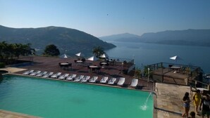 A poolside area with lounge chairs and umbrellas, overlooking a body of water and mountains. - Flat Angra dos Reis Portogalo (Angra dos Reis)