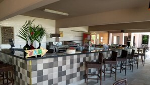 A bar area with a checkered tile design, wicker chairs, and a counter with a 'BAR' sign. - Flat Angra dos Reis Portogalo (Angra dos Reis)