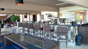 A spacious kitchen with a bar area, wicker furniture, and a glass-top dining table. - Flat Angra dos Reis Portogalo (Angra dos Reis)