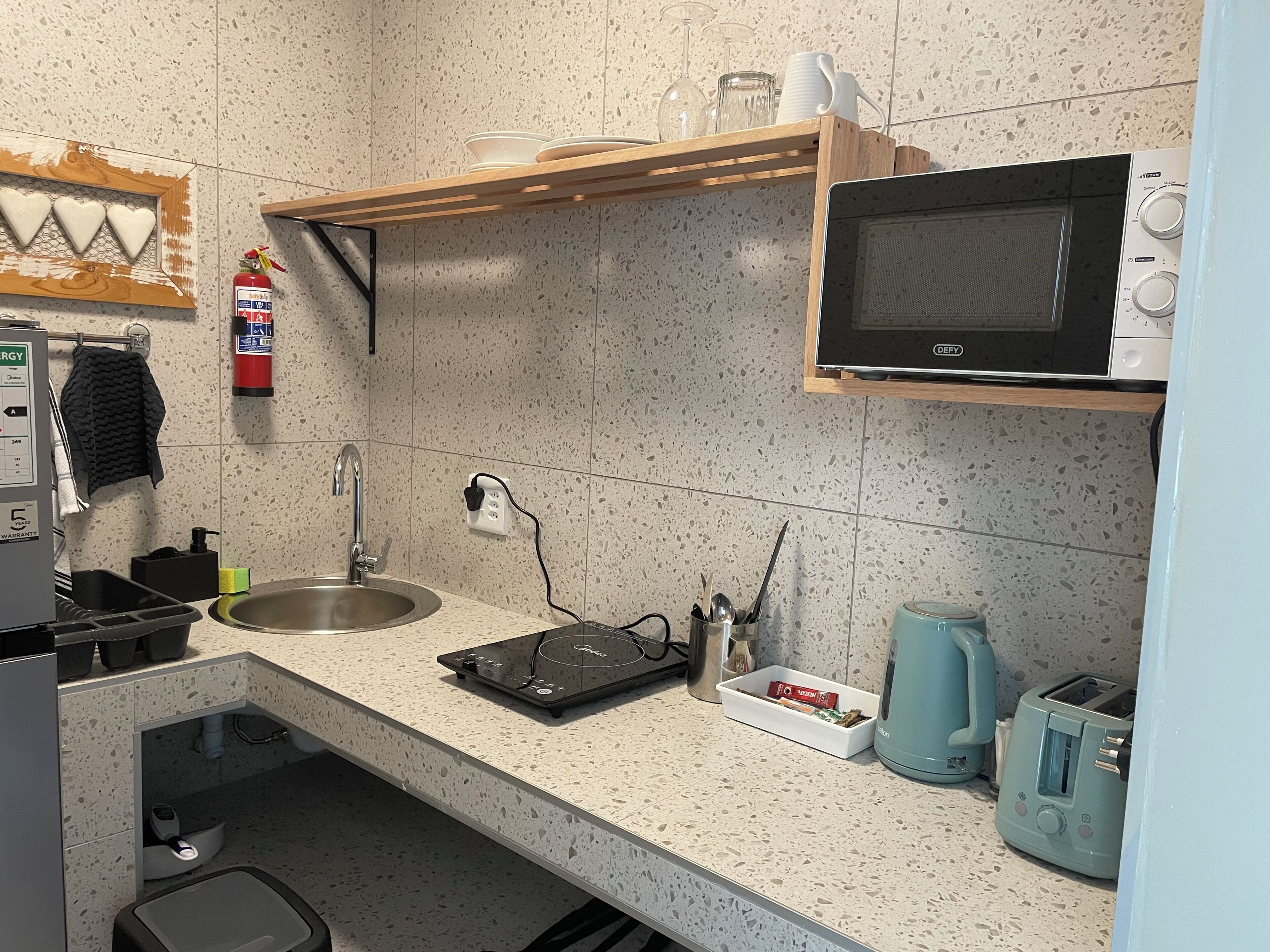 Una cocina con un lavamanos, un microondas, un tostador y una tetera.