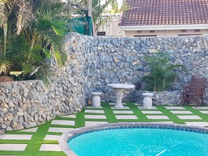 Relax by the pool surrounded by lush greenery and stone features.