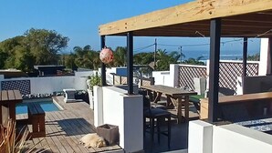Une terrasse sur le toit, aménagée avec du mobilier d’extérieur, une piscine et une vue sur l’océan.