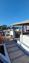 Una terraza en la azotea con mobiliario exterior, una piscina y vistas al océano.