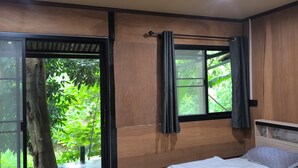 A bedroom with a bed, a sliding glass door leading to a balcony, and a window with curtains. - Hill Tribe Art House (Chiang Rai)