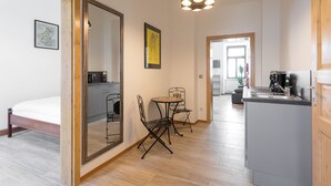 A modern kitchen with a built-in island, a dining area with a small table and chairs, and a large mirror reflecting the space.
