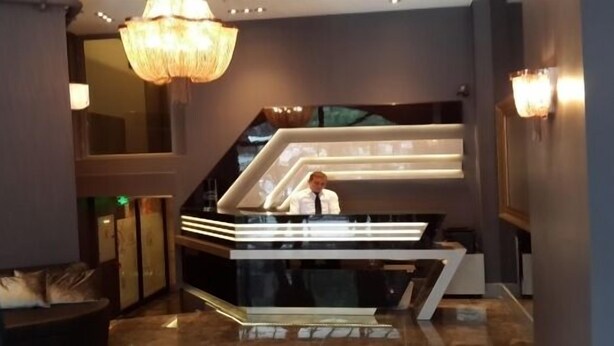 A modern reception area with a glass counter and a person standing behind it. - Reda Palas Karanfil (Ankara)