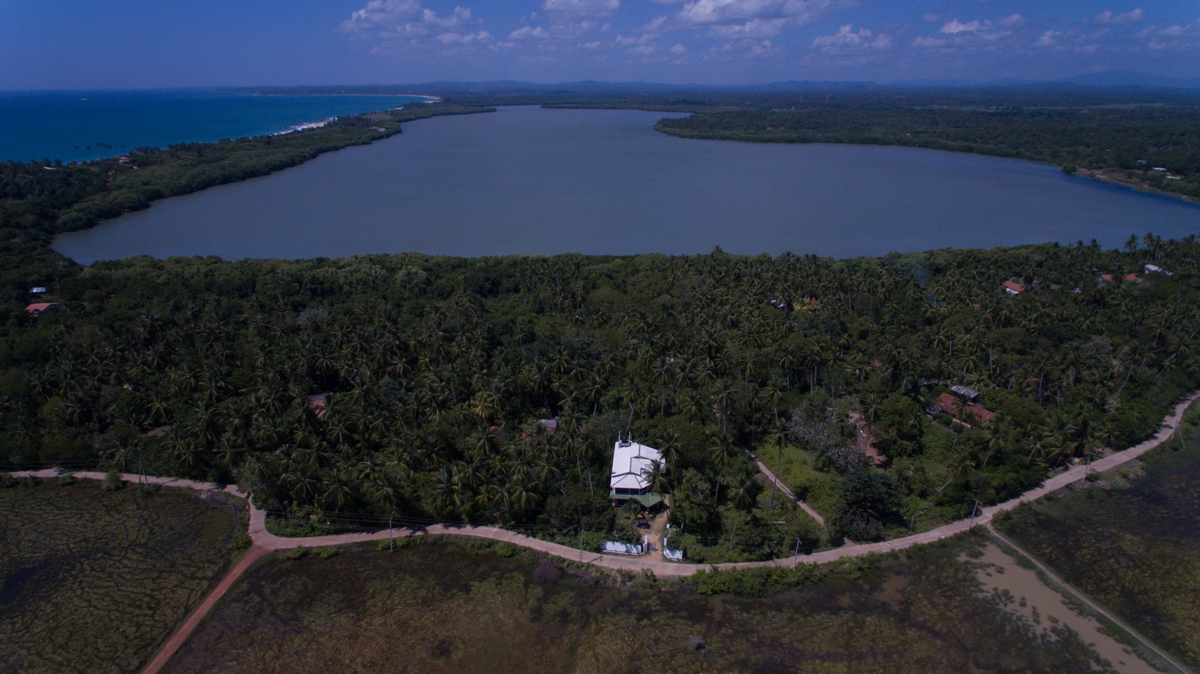 Vue aérienne d’un grand lac entouré d’une forêt dense et de quelques bâtiments dispersés.