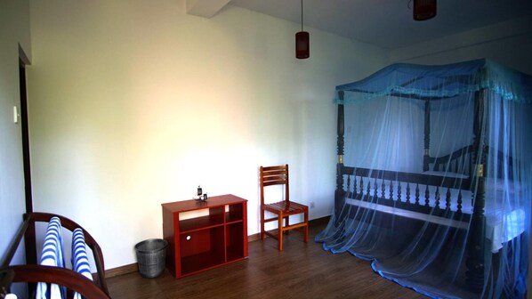 A bedroom with a wooden bed, a chair, a small desk, and a hanging light fixture. - All view resort (Rekawa)