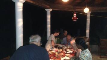 A group of people dining at an outdoor table with a chandelier overhead.