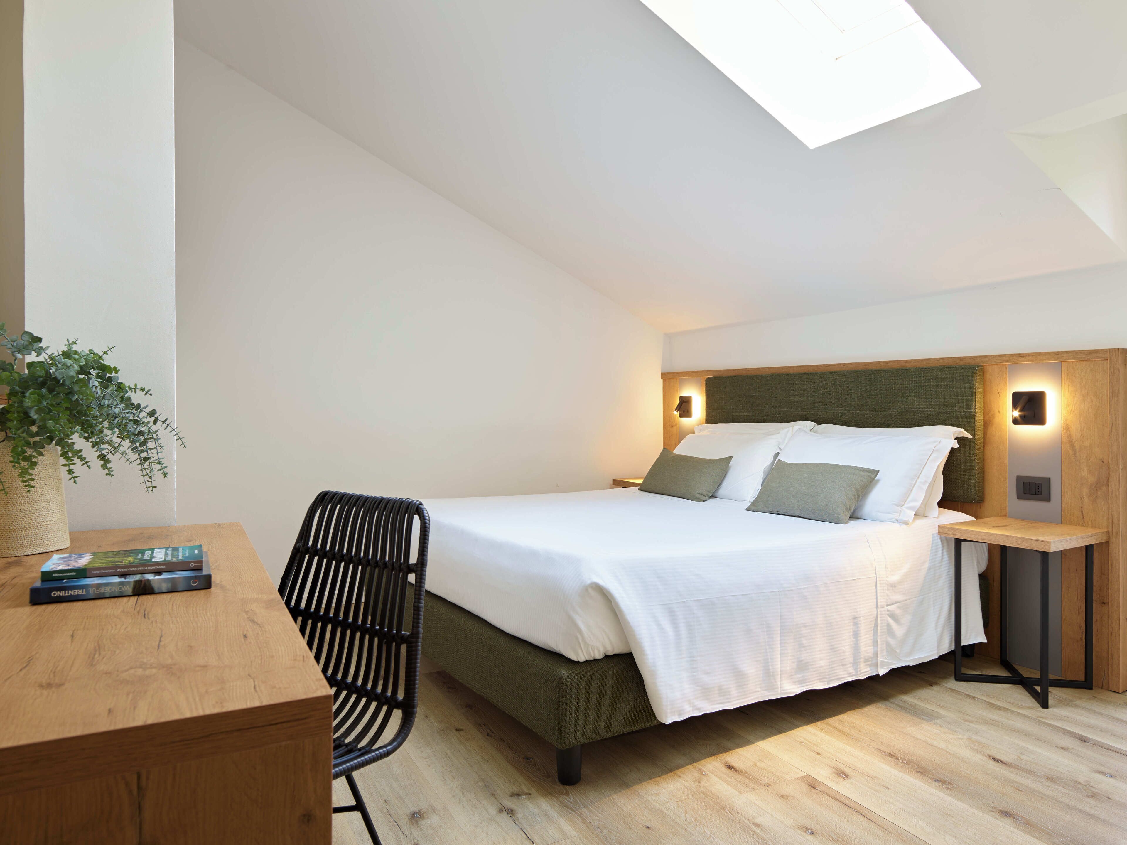 A modern bedroom with a bed, bedside tables, a desk, and a chair.