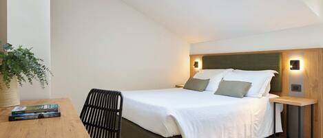 A modern bedroom with a bed, bedside tables, a desk, and a chair.