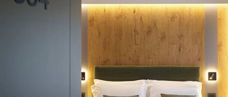 Habitación de hotel con una cama grande, cabecero de madera y el número '554' en la pared.