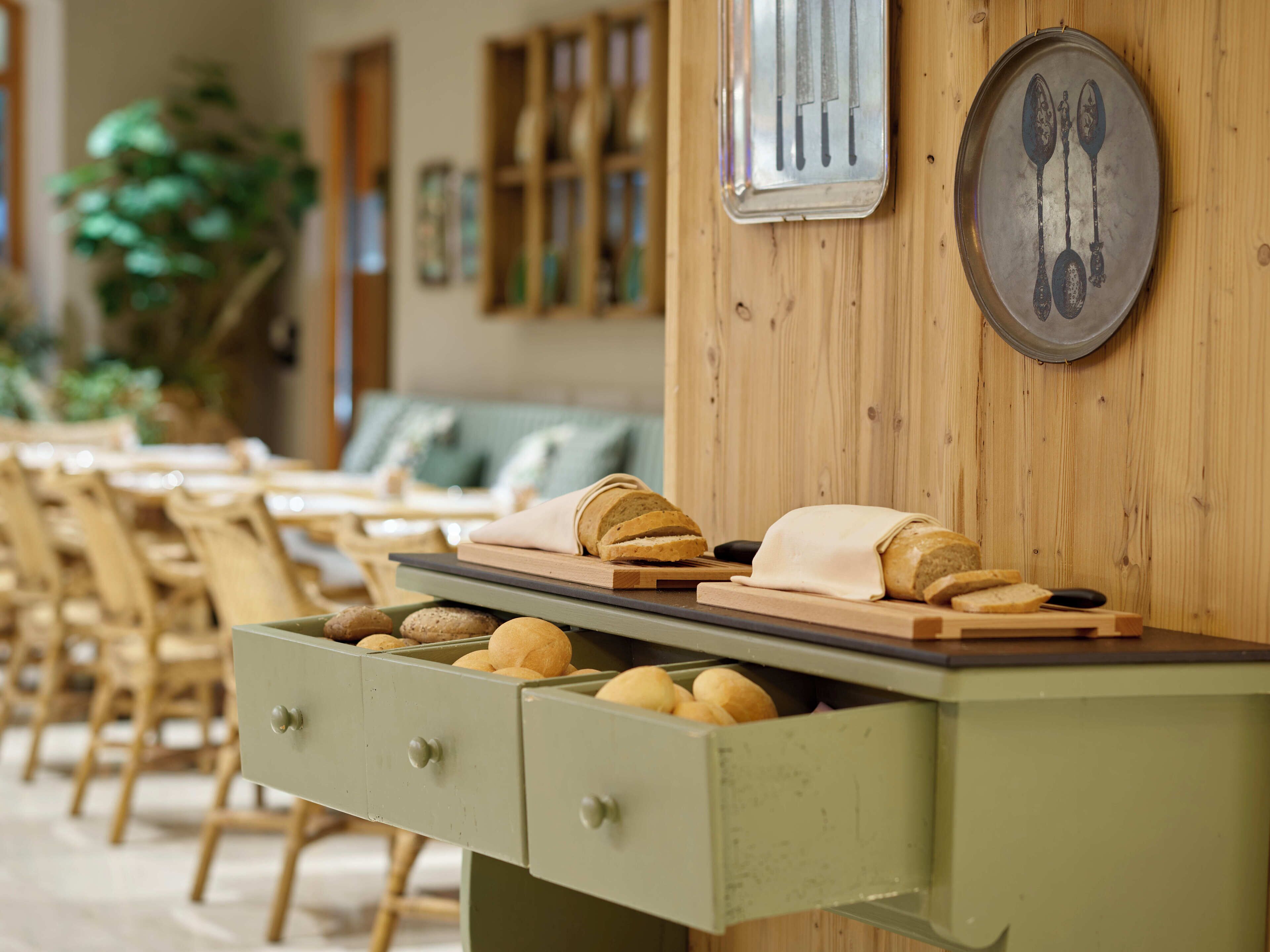 A dining area with wooden furniture, a bread display, and a wall-mounted utensil holder.