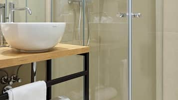 A modern bathroom with a glass-enclosed shower, a white vessel sink, and a wooden vanity.