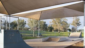 Pista de skate ao ar livre com rampas e uma área de estar coberta.