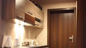Una cocina con armarios de madera, horno empotrado y una puerta de madera oscura.