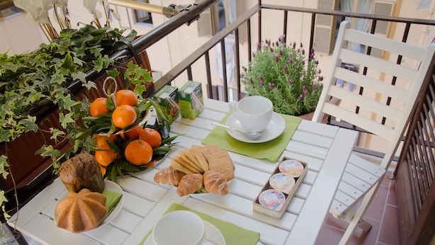 A balcony with a table set for a meal, including bread, oranges, and a cup. - Castellani a San Pietro (Rome)