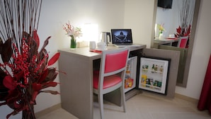 A compact hotel room with a desk, a laptop, a refrigerator, and a red chair. - Castellani a San Pietro (Rome)