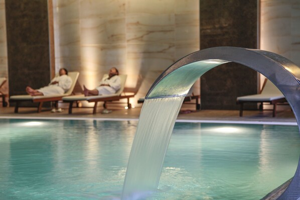 A pool with a water feature in the foreground and lounge chairs in the background. - Gulumser Hatun Termal Otel & Spa (Kutahya)
