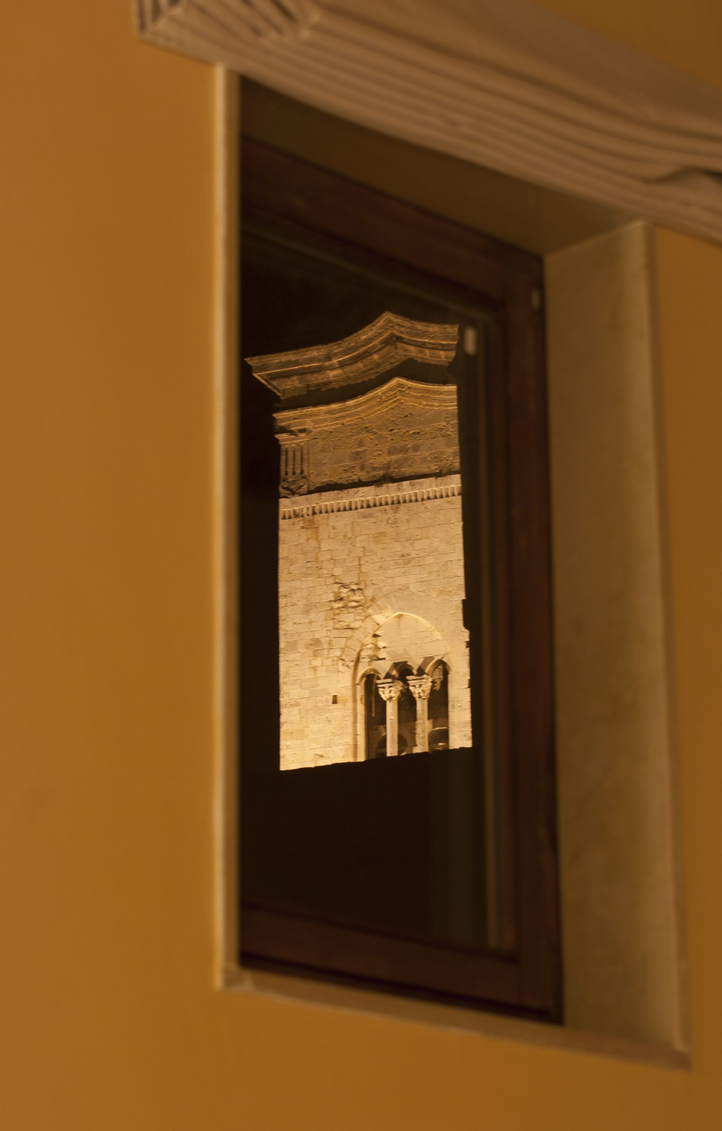 Una ventana con vistas a un edificio de piedra con arcos y columnas.