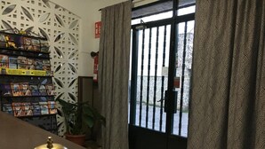 A reception area with a bookcase, a potted plant, and a black door with a patterned curtain.