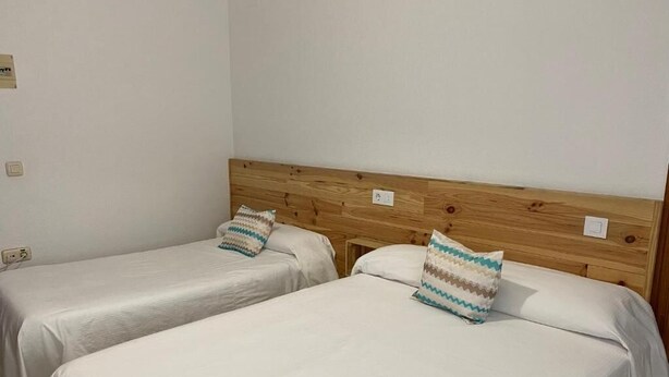 Two single beds with wooden headboards and white bedding.