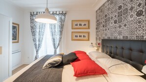 Une chambre à coucher avec un grand lit, une tête de lit capitonnée et un papier peint à motifs.