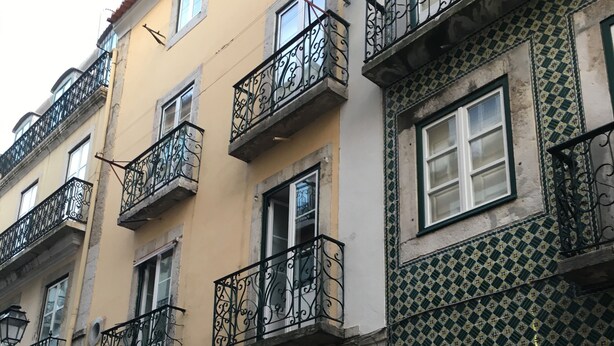 Un immeuble à plusieurs étages doté de balcons, avec un commerce au rez-de-chaussée et une enseigne indiquant le numéro 28.