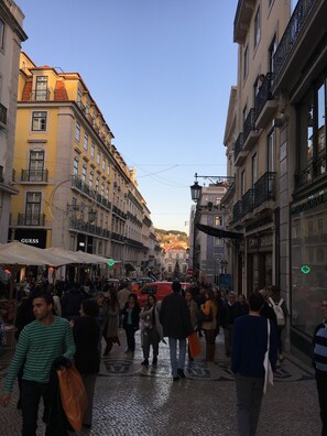A busy street with pedestrians, shops, and buildings with balconies and signage.
