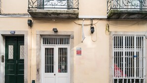 Un bâtiment avec une porte verte, une porte blanche dotée de fenêtres grillagées et une fenêtre grillagée sur laquelle est apposée une enseigne rouge.