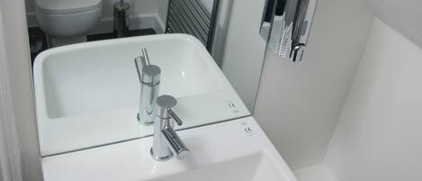 Une salle de bain blanche avec un lavabo, des toilettes et un miroir.